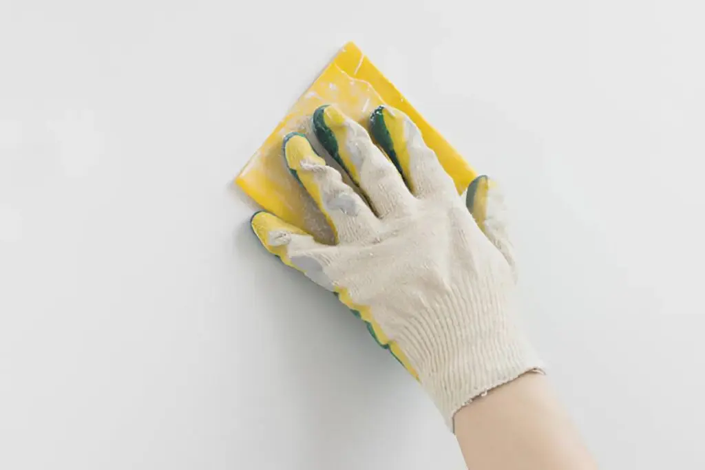 Painter in Melbourne, FL, preparing a commercial wall with sanding before painting
