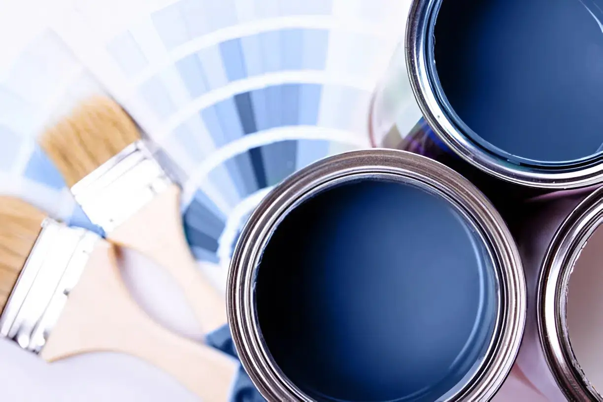 Open paint cans, brushes, and color swatches used by an exterior painter in Melbourne, FL, for seasonal home projects
