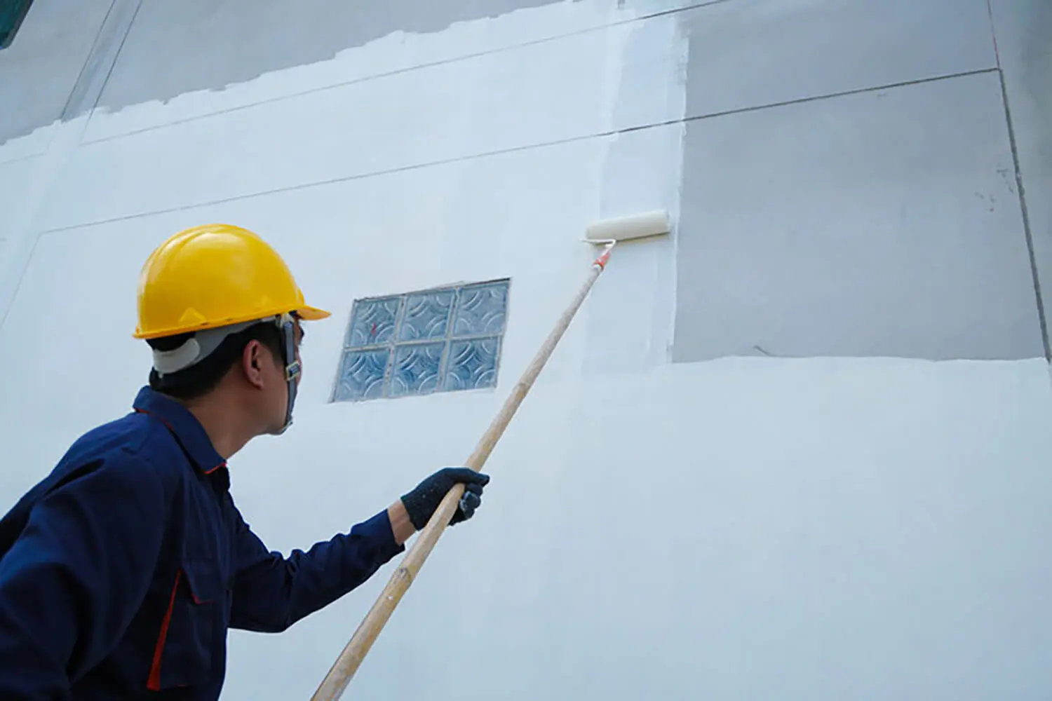 Commercial painter applying fresh paint to an interior wall during a project, addressing common questions about commercial painting projects such as prep, coverage, and finish quality.